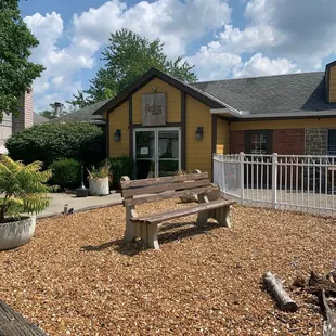 a wooden bench in front of a yellow house