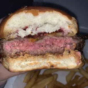 a hand holding a hamburger and fries