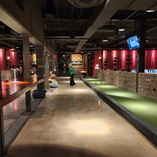 people playing mini golf in a bowling alley