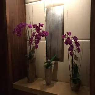 two vases of flowers on a shelf