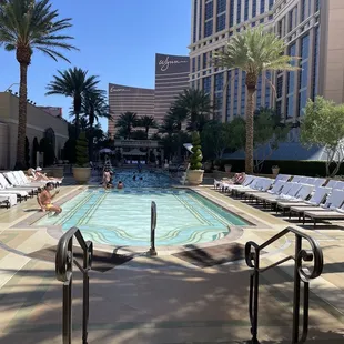 a swimming pool with lounge chairs and palm trees