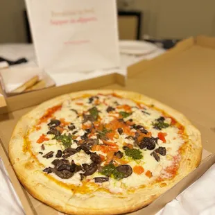 Signature pizza with mushrooms, basil, tomatoes and Italian sausage