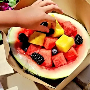 a child reaching for a watermelon