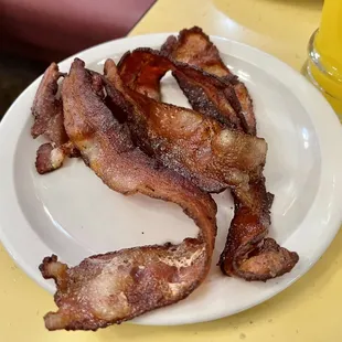 a plate of bacon and a glass of orange juice