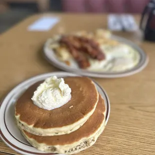 a stack of pancakes with bacon and eggs