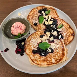 Lemon Ricotta Pancakes with blueberry compote, almonds, and lemon blueberry butter shaped into a rose.