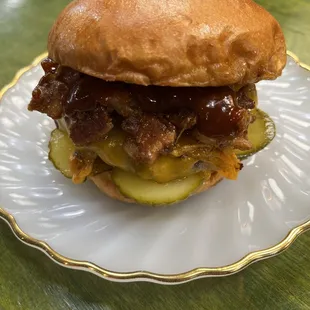 a hamburger with pickles and barbecue sauce