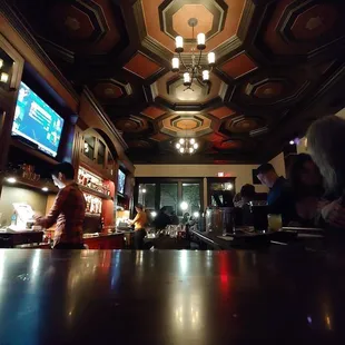 people sitting at a bar watching televisions