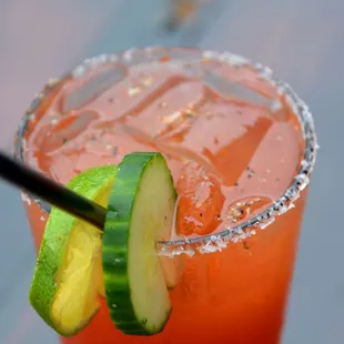 a drink with a cucumber garnish