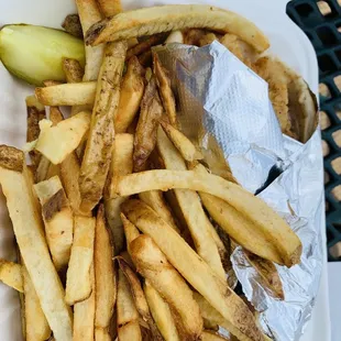 french fries and a pickle in a styrofoam container