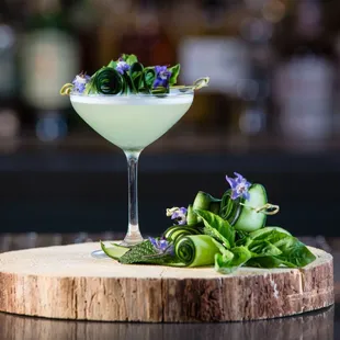 a cocktail in a martini glass with a garnish of flowers