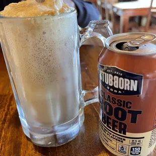 a glass of root beer next to a can of root beer