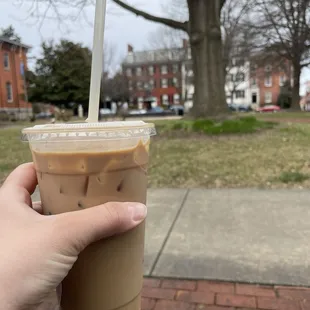 a hand holding a cup of iced coffee