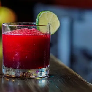a red drink with a lime slice on the rim
