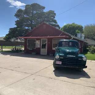a green truck parked in front of a red building