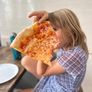 a little girl eating a slice of pizza