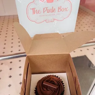 a chocolate cupcake in a pink box