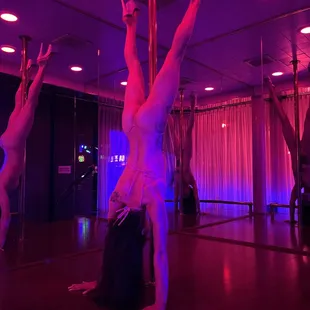 a woman doing a handstand on a pole
