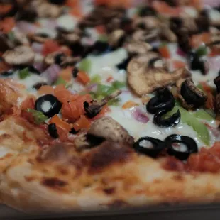 a closeup of a pizza with mushrooms, peppers, and black olives