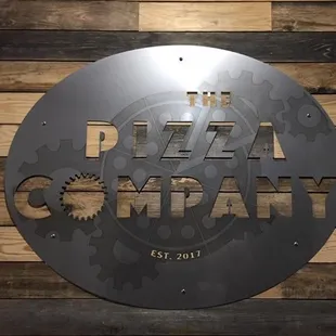 a circular metal sign on a wooden wall