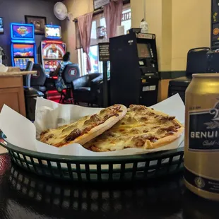 a basket of pizza and a can of beer