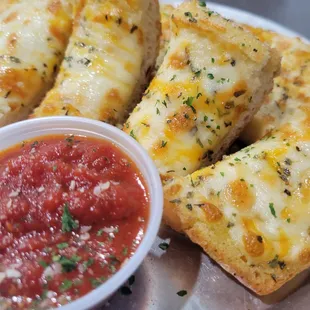 a plate of pizza sticks and a bowl of sauce