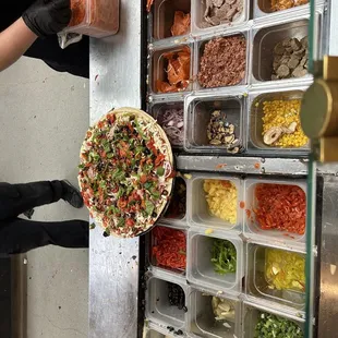 a person putting toppings on a pizza
