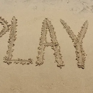 the word playa written in the sand