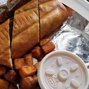 a sandwich and tater tots in a styrofoam container