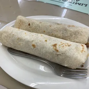 two burritos on a plate with a fork