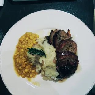 bacon wrapped meatloaf with mashed potatoes and a corn succotach