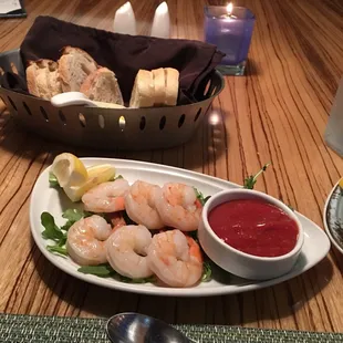 a plate of shrimp, bread, and dipping sauce