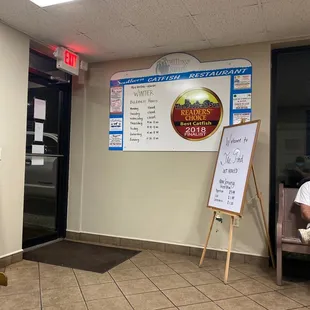 a man sitting in a chair in front of a menu board