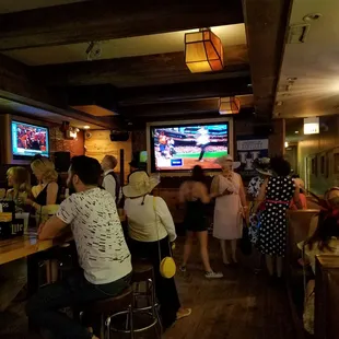 people sitting at a bar watching televisions