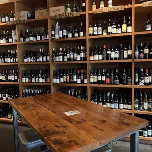 a table and chairs in front of a wall of wine bottles