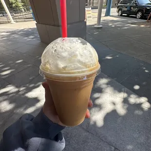 a hand holding a cup of iced coffee