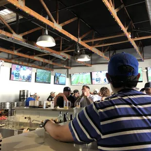 a man sitting at a bar watching televisions