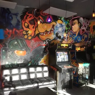 Cozy game room with couches, board games, and coin-op arcade console games