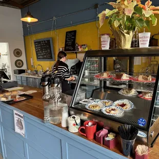 a woman standing at a counter in a bakery