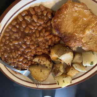 a plate of baked beans, potatoes, and meat