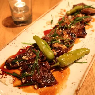Kalbi beef short ribs with fried garlic, cashew bits, scallion, ginger soy glaze and pickled shishito peppers.