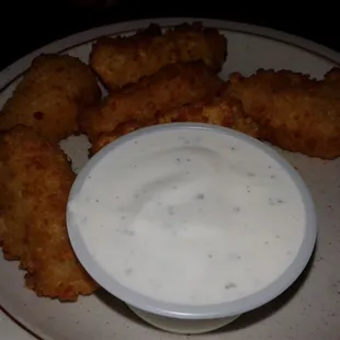 a plate of fried chicken nuggies and a bowl of ranch dip