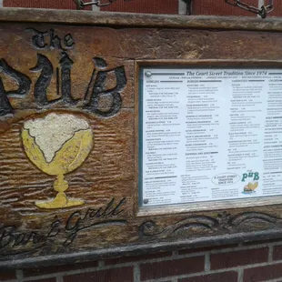 a menu and a plaque on a brick wall