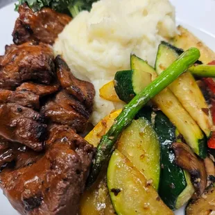 Steak tips, mash potatoes, and sautéed vegetables