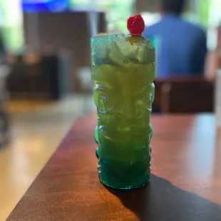 a green drink with a cherry on top