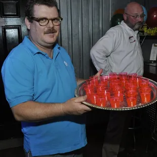 a man holding a tray of red cups