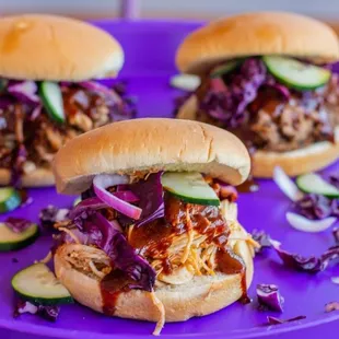 two pulled pork sandwiches on a purple plate