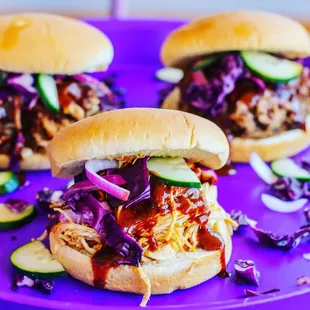 two pulled pork sandwiches on a purple plate