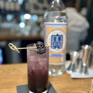 a drink with a black berry garnish