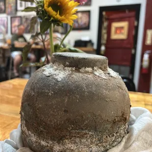 a vase with a sunflower in the background